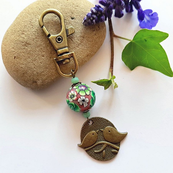 medalla llavero d&uacute;o de p&aacute;jaros color bronce y perla artesanal motivo floral verde y vino l&iacute;asmulticolor
