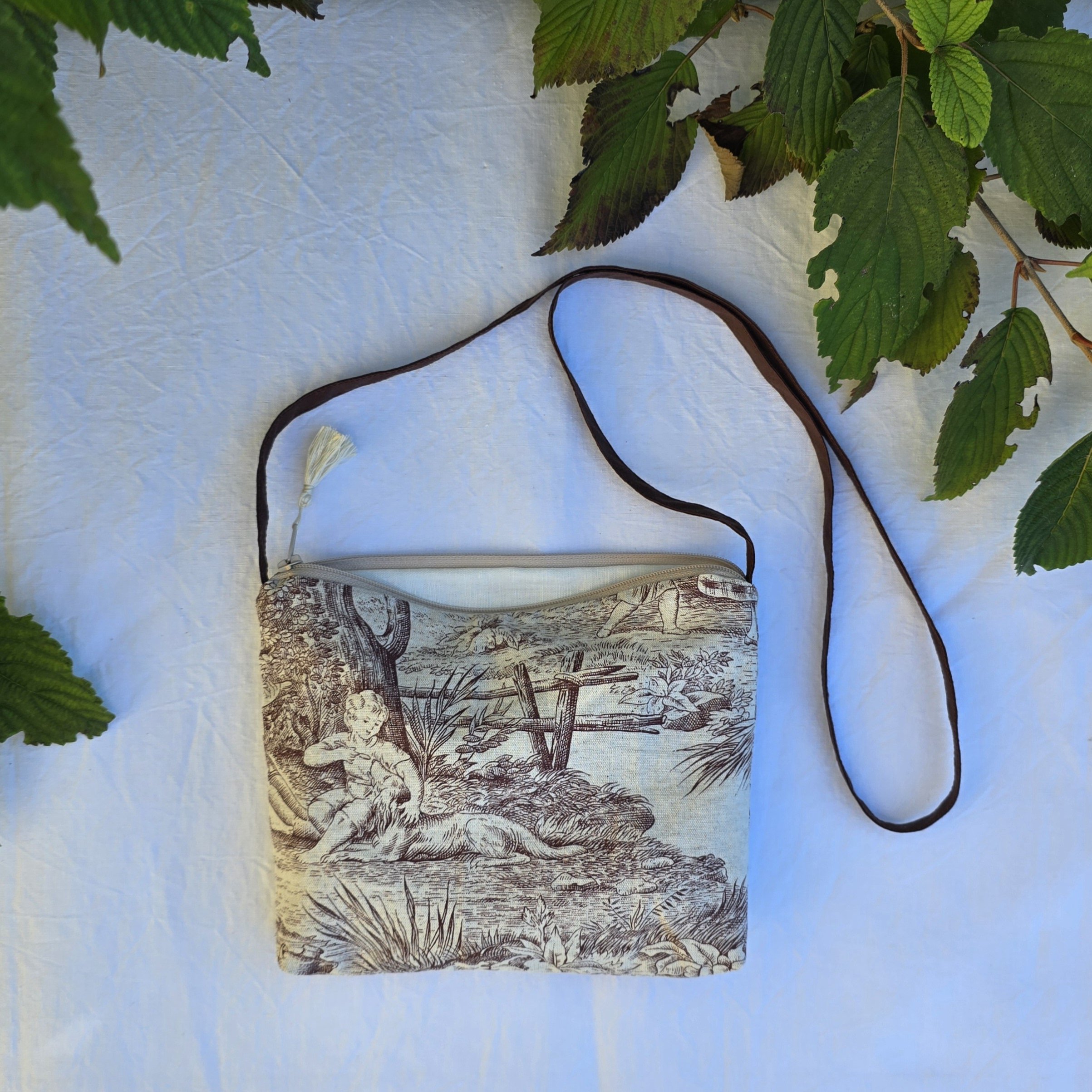 Pochette avec bandouli&egrave;re en tissu toile de Jouy marron et beige agr&eacute;ment&eacute;e d'un pompon