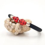 Pulsera doble de calavera y tibias cruzadas con piedras rojas sobre una gruesa cuerda negra