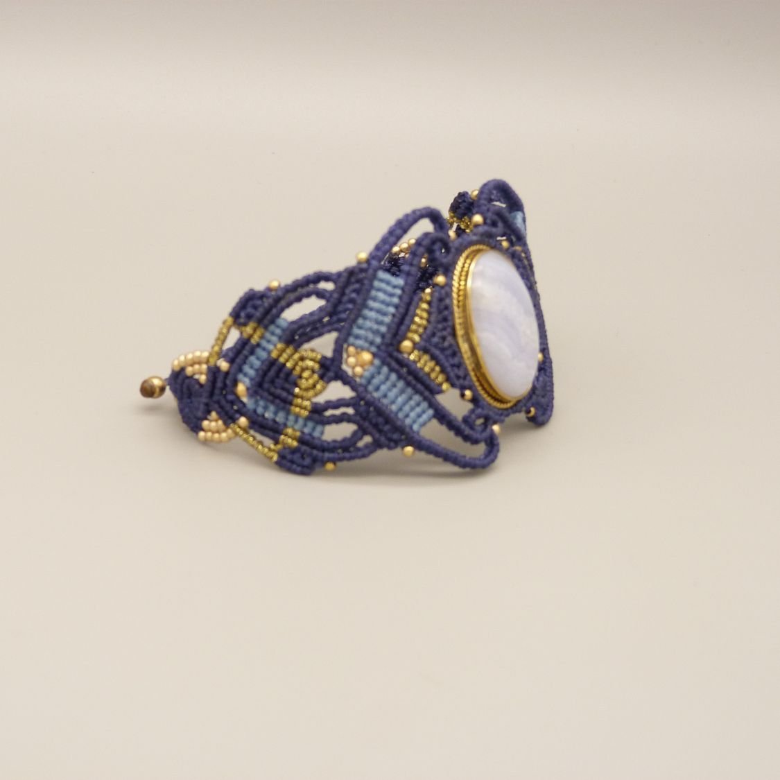 Pulsera de micromacramé azul noche con una cinta de ágata engastada en metal dorado