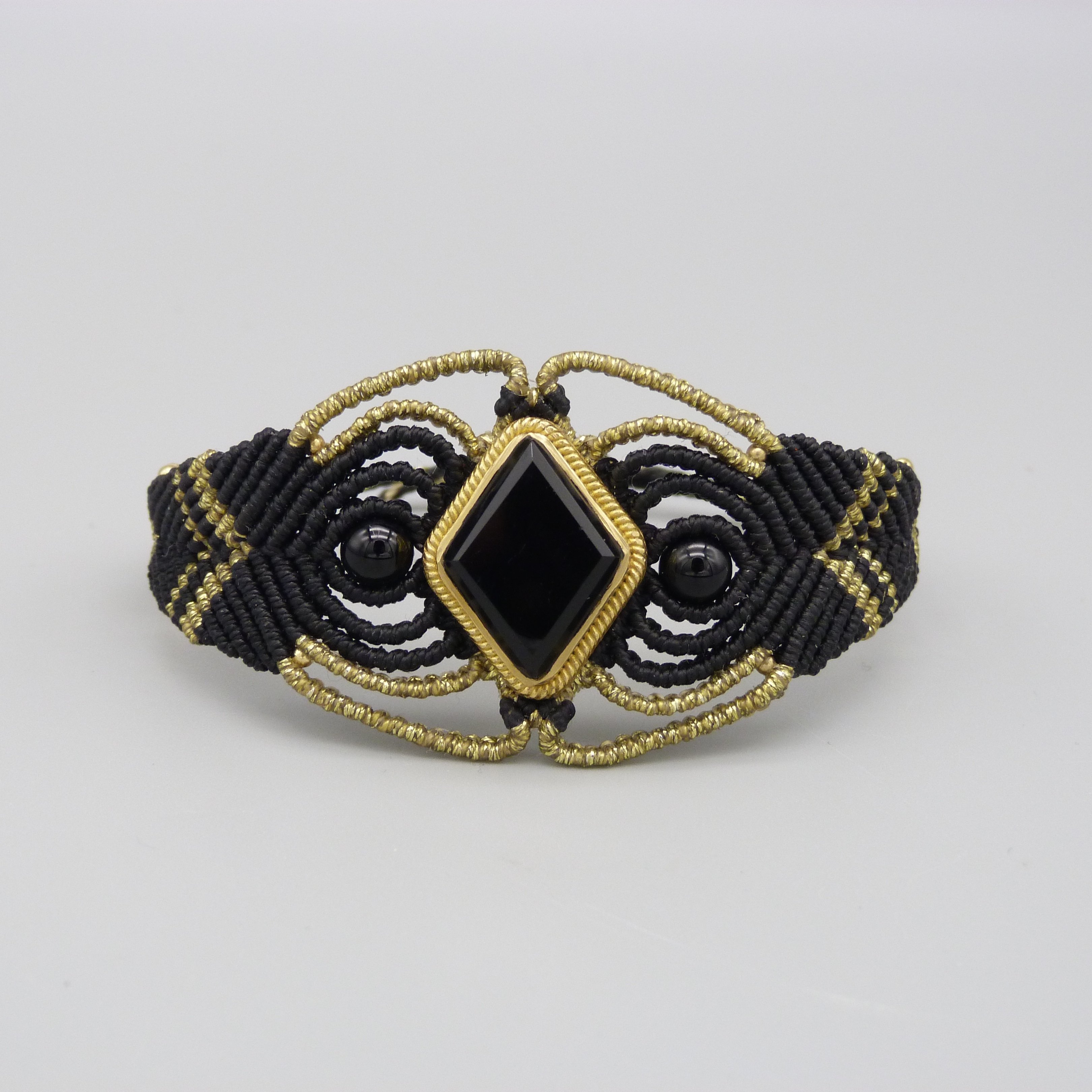 Manchette noire en micro-macram&eacute; avec une pierre onyx noire sertie de laiton