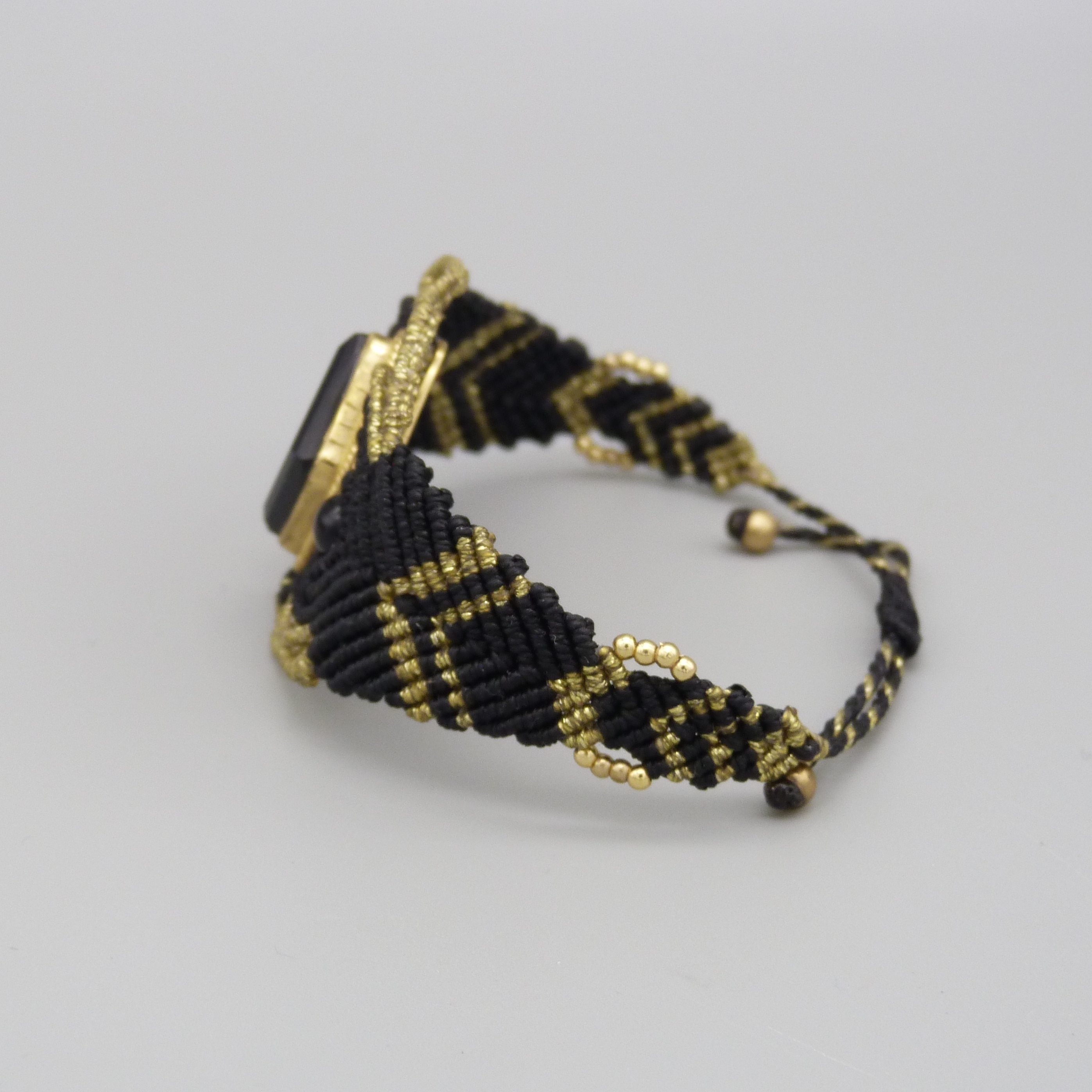 Manchette noire en micro-macramé avec une pierre onyx noire sertie de laiton