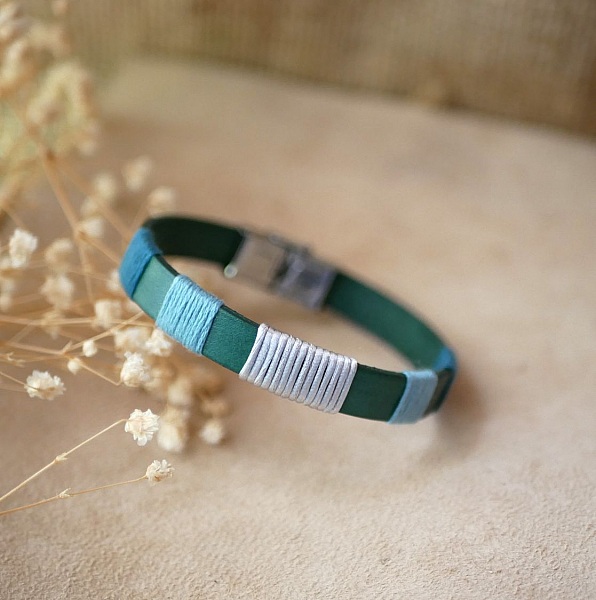 Bracelet en cuir vert tissé de fils bleu et argent.