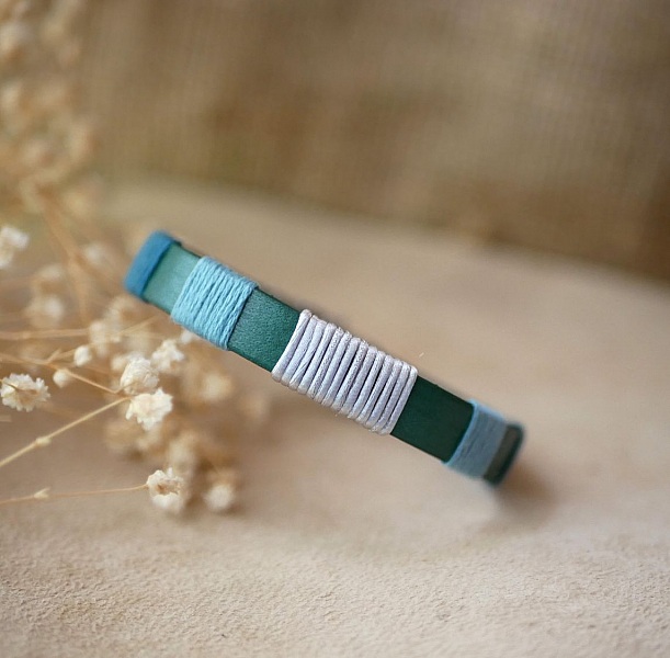 Bracelet en cuir vert tissé de fils bleu et argent.