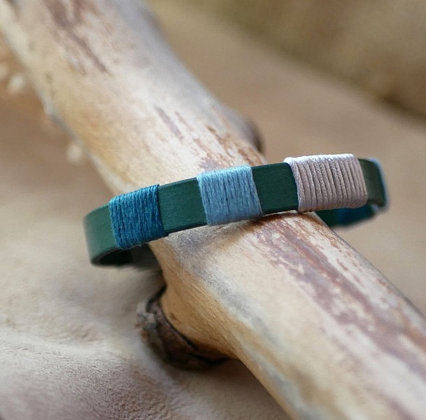 Bracelet en cuir vert tissé de fils bleu et argent.