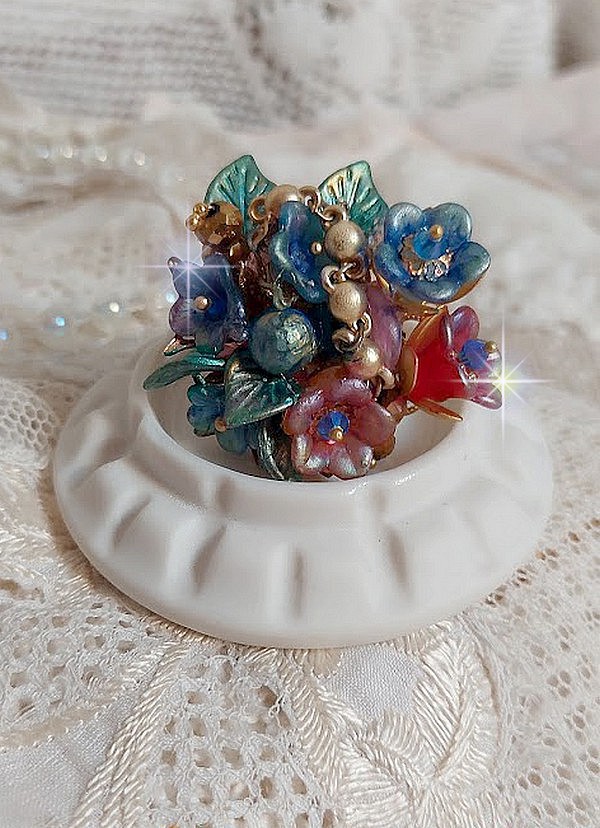 Bague Bel Air montée avec des fleurs lucites peintes à la main aux couleurs : Bleu, Rose, Rouge, Argent, Blanc avec feuilles ondulées Vert Cuivré à laquelle s’ajoute perles Dorées en Verre