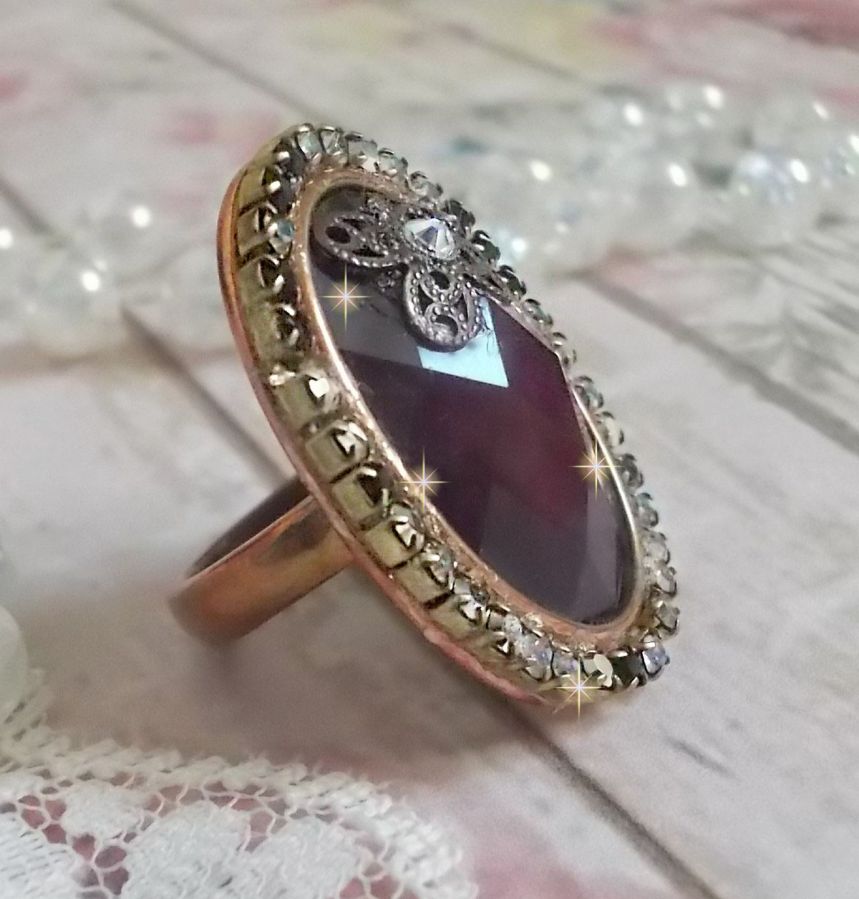 Elegante anillo burdeos creado con cristales PureCrystal, un sello en forma de flor y un cabujón de cristal.