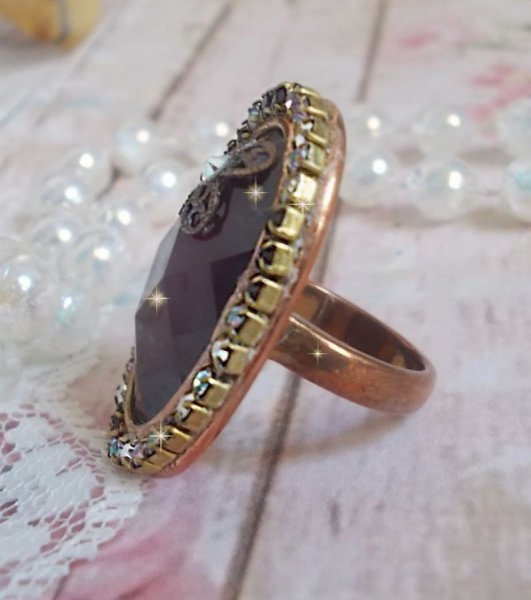 Elegante anillo burdeos creado con cristales PureCrystal, un sello en forma de flor y un cabuj&oacute;n de cristal.