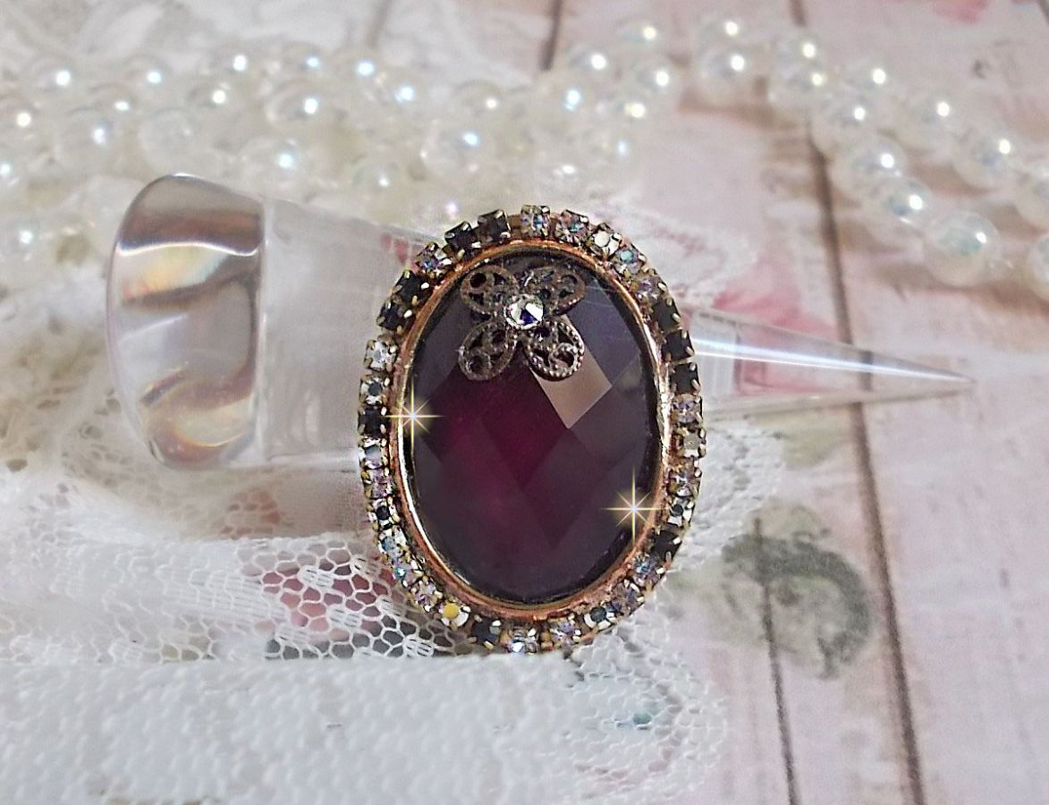 Elegante anillo burdeos creado con cristales PureCrystal, un sello en forma de flor y un cabujón de cristal.