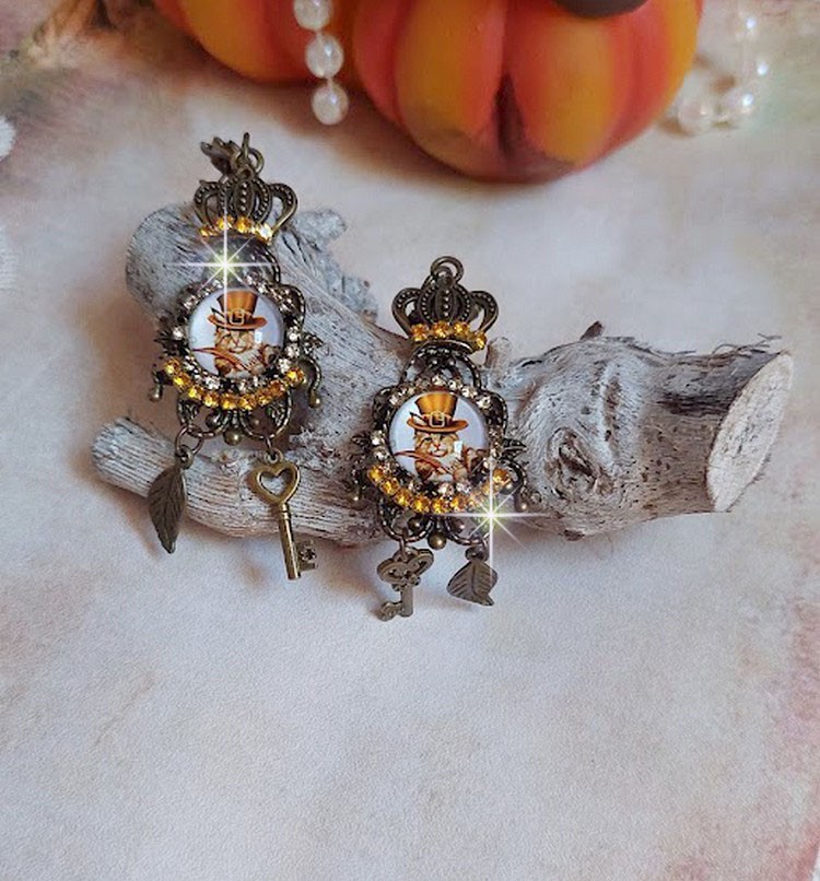 BO Chatibo Steampunk montées avec cabochons ronds en verre représentant un chat chapeauté Haute de Forme Orange. Strassées avec une couronne, breloques clés et feuilles. Montées sur clips Bronze