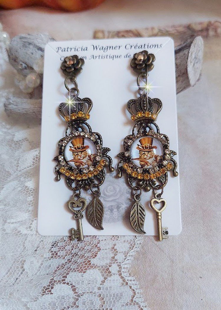 BO Chatibo Steampunk montées avec cabochons ronds en verre représentant un chat chapeauté Haute de Forme Orange. Strassées avec une couronne, breloques clés et feuilles. Montées sur clips Bronze