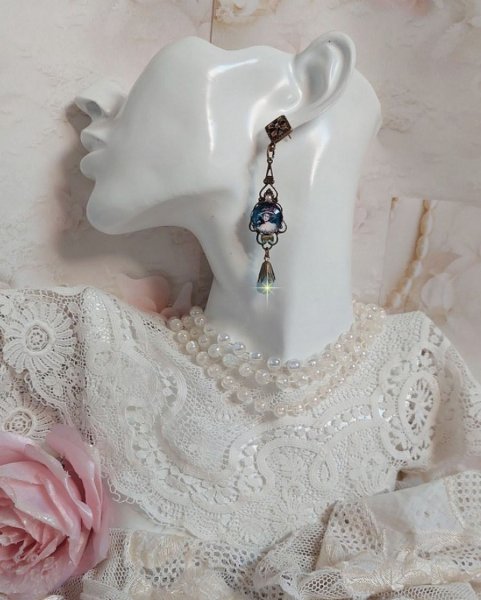 BO Dame au chapeau fleuri repr&eacute;sentant une femme au chapeau entour&eacute; d&rsquo;un ruban noir est mont&eacute; sur des estampes avec des n&oelig;uds en cristal. Une belle &eacute;l&eacute;gance avec ces gouttes en Jade teint&eacute;es de Bleu