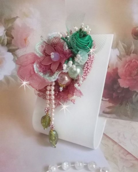 Broche de polvo suave creado con encaje, cinta de organza, cuentas de Swarovski, cuentas de cristal y cuentas de rocalla 