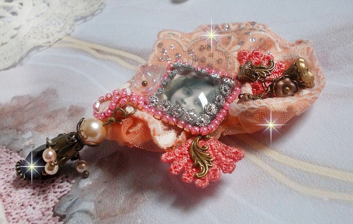 Broche Rosa rústica creado con un cabujón que representa una niña sonriente, strass naranja y encaje rosa, cristales, cuentas de vidrio y accesorios varios