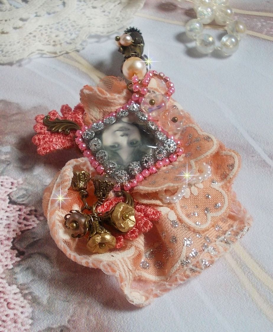 Broche Rosa rústica creado con un cabujón que representa una niña sonriente, strass naranja y encaje rosa, cristales, cuentas de vidrio y accesorios varios