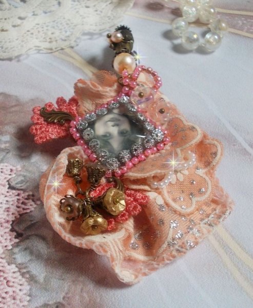 Broche Rosa r&uacute;stica creado con un cabuj&oacute;n que representa una ni&ntilde;a sonriente, strass naranja y encaje rosa, cristales, cuentas de vidrio y accesorios varios