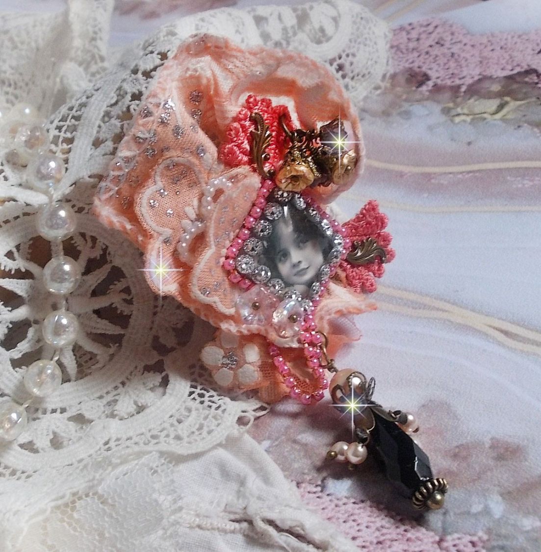 Broche Rosa rústica creado con un cabujón que representa una niña sonriente, strass naranja y encaje rosa, cristales, cuentas de vidrio y accesorios varios