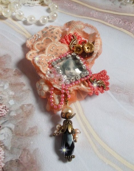 Broche Rosa r&uacute;stica creado con un cabuj&oacute;n que representa una ni&ntilde;a sonriente, strass naranja y encaje rosa, cristales, cuentas de vidrio y accesorios varios