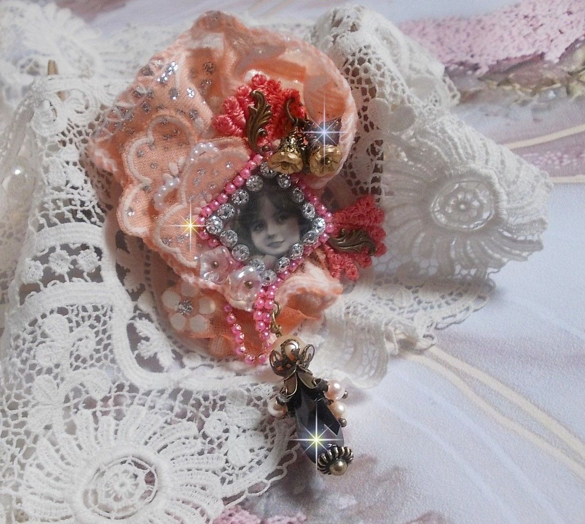 Broche Rosa rústica creado con un cabujón que representa una niña sonriente, strass naranja y encaje rosa, cristales, cuentas de vidrio y accesorios varios