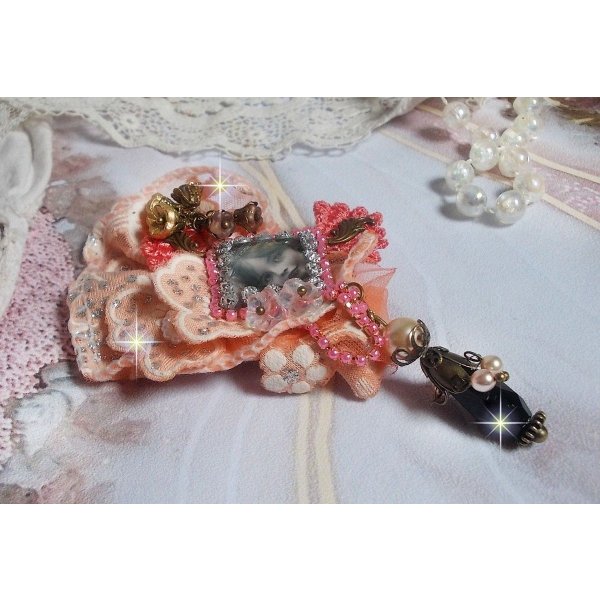 Broche Rosa r&uacute;stica creado con un cabuj&oacute;n que representa una ni&ntilde;a sonriente, strass naranja y encaje rosa, cristales, cuentas de vidrio y accesorios varios