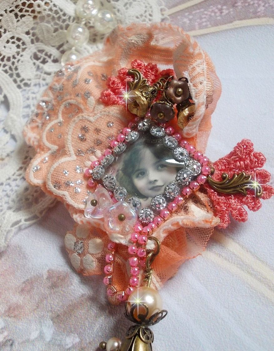 Broche Rosa rústica creado con un cabujón que representa una niña sonriente, strass naranja y encaje rosa, cristales, cuentas de vidrio y accesorios varios