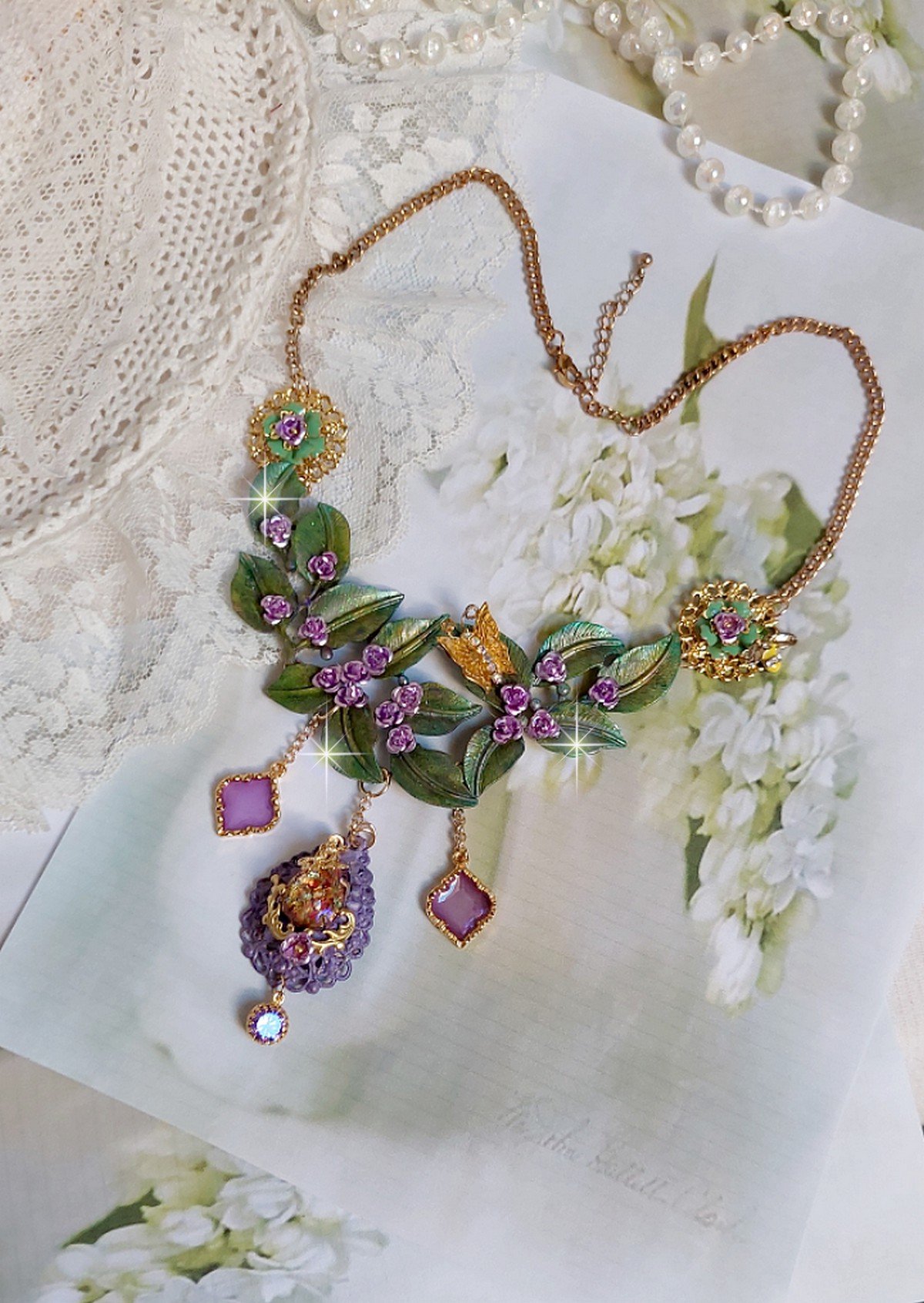 Collier Camélia Japonica monté avec un motif feuilles aquarellés à la main, paillettes, breloques papillons et abeille, roses métal, cabochon cristal, pendentifs époxy aux couleurs d’arc en ciel