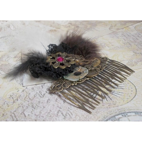 Peineta Curiosity Time creada con encaje negro, varios accesorios, dijes de oro, plata y bronce con plumas negras, marrones y blancas.