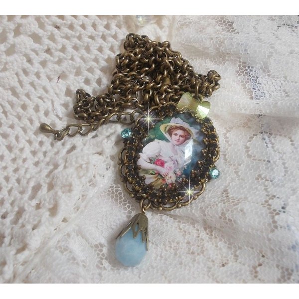Pendentif Douce Dame cr&eacute;&eacute; avec un cabochon repr&eacute;sentant une femme au chapeau blanc orn&eacute; de cristaux, des accessoires de couleur Bronze et un jade teint&eacute; bleu 