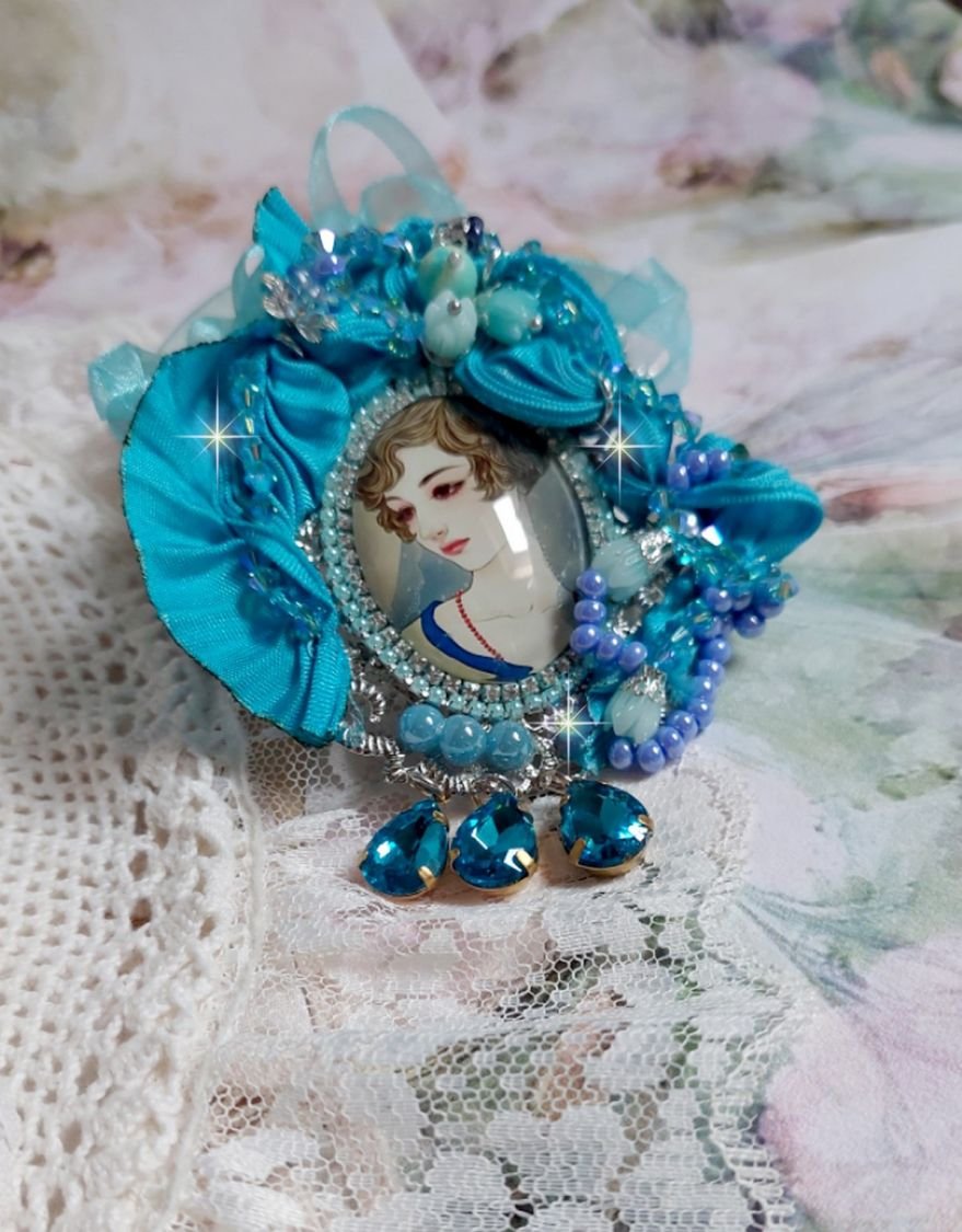 Pendentif Mademoiselle au style rétro avec cabochon d’une femme souriante, orné d’un ruban de soie Bleu, cristaux, perles verre : rocailles et roses, coupelles et chaîne Argent 925/1000