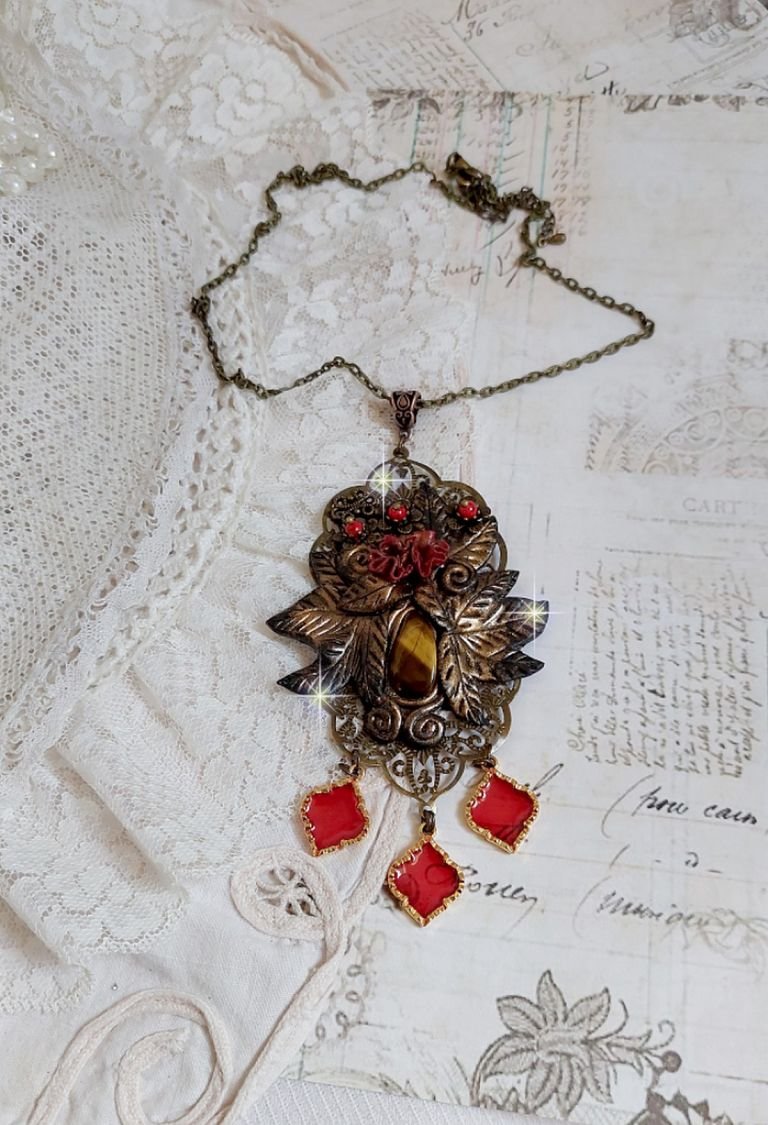 Pendentif Mélodie avec un cabochon Œil de tigre orné de perles en Jade Rouge veiné de Noir sur fleurs 5 pétales et estampes montés sur une chaîne bronze. Les pendants sont en résine époxy Rouge