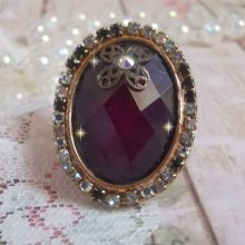 Elegante anillo burdeos creado con cristales PureCrystal, un sello en forma de flor y un cabujón de cristal.