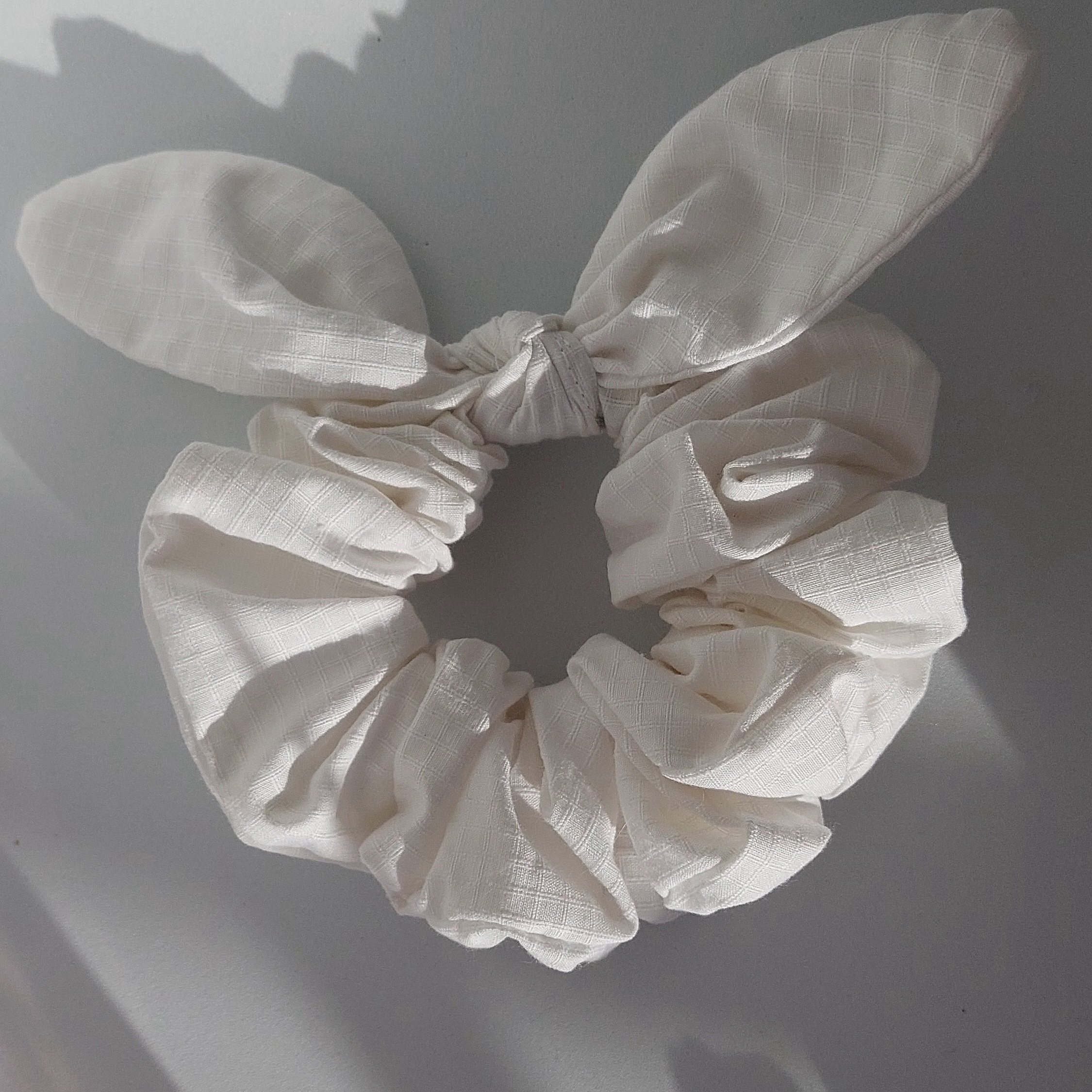 Chouchou foulchie blanc à carreaux sur fond rose.